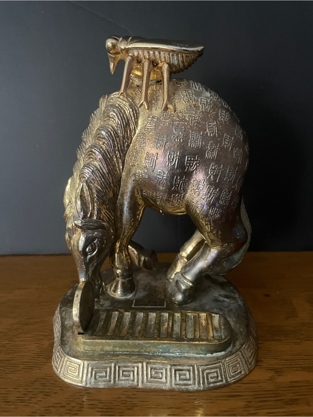 A brass sculpture of a horse with an insect and Chinese calligraphy.